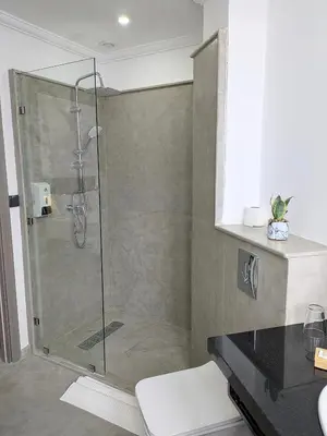a shower with a glass door in a bathroom at Hôtel Les Remparts in Azemmour