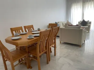 a dining room with a table and chairs and a couch at Apparemment Meuble a 5 min de l'aéroport casa in Nouaceur