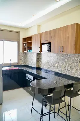 a kitchen with a black counter and some chairs at Les portes de Temara in Temara