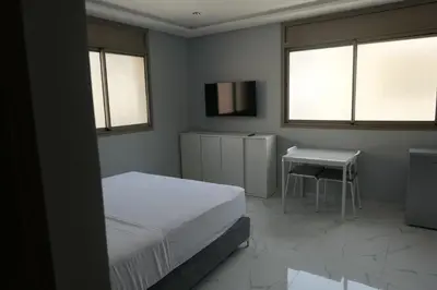 a bedroom with a bed and a table and two windows at Les portes de Temara in Temara