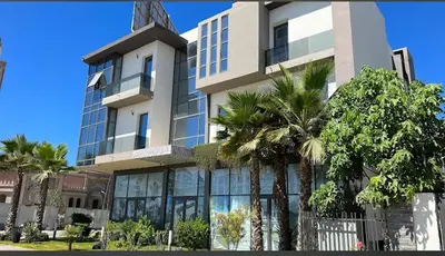a building with palm trees in front of it at Les crêtes dar bouazza in Casablanca