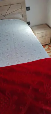 a bed with a red and white comforter on it at Appartement à Bernoussi Casablanca in Casablanca