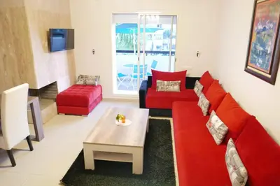 a living room with a red couch and a table at Appartement Haut Standing - Bouznika plage in Bouznika