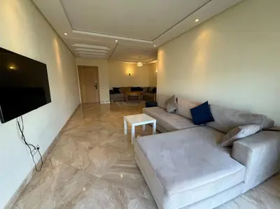 a living room with a couch and a flat screen tv at Sublime appart piscines & espaces jeux, proche mer in Bouznika