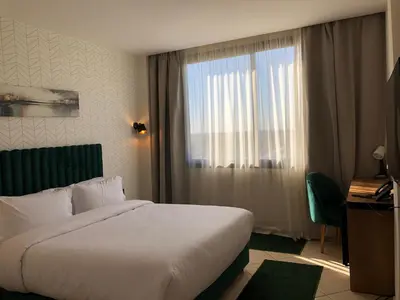 a hotel room with a bed and a window at Hôtel Hariz Son in Berrechid