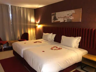 a hotel room with a large bed with flowers on it at Hôtel Hariz Son in Berrechid