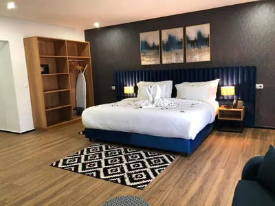 a bedroom with a large bed and a rug at Hôtel Hariz Son in Berrechid