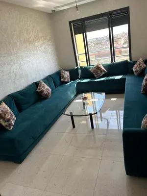 a living room with a green couch and a glass table at Appartement à Sidi Rahal - 5 min de la plage in Sidi Rahal