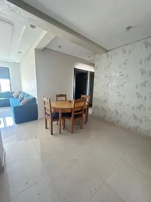 a dining room with a table and chairs and a couch at Appartement à Sidi Rahal - 5 min de la plage in Sidi Rahal