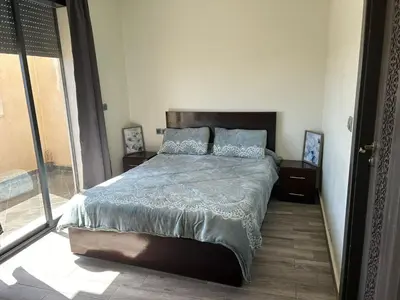a bedroom with a bed and a large window at Appartement à Sidi Rahal - 5 min de la plage in Sidi Rahal