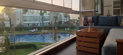 a living room with a couch and a swimming pool at Les perles de Tamaris in Dar Mohammed Ould Haj Jilali