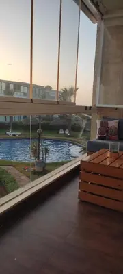a living room with a view of a swimming pool at Les perles de Tamaris in Dar Mohammed Ould Haj Jilali