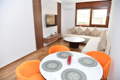 a living room with a table and orange chairs at Superb appartement au centre ville in Rabat