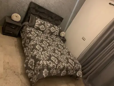 a bed with a black comforter and two pillows at appartement de antoine in Maarif