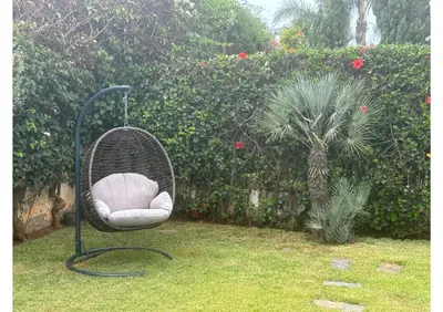 a wicker chair sitting in the grass in a garden at Villa luxe avec piscine in Oulad Hamida