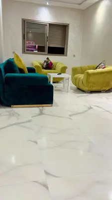 a living room with two blue couches and white floors at Bel appartement à louer sur bouznika de 117 m2 in Bouznika