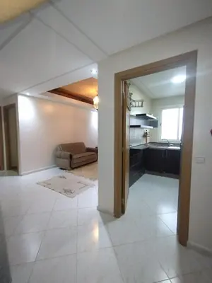 a living room with a couch and a kitchen at Appartement très propre lumineux en moyen standing a résidence klk darbouza in Casablanca