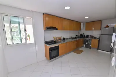 a kitchen with wooden cabinets and a stainless steel appliance at Cozy Duplex appartement wifi parking proximité in Rabat