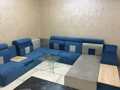 a living room with a blue couch and a glass table at larc in Deroua