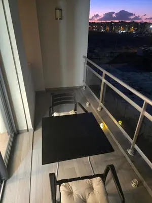 a room with a table and chairs on a balcony at Charmant appartement à 10min de L' Aéroport Med V in Nouaceur
