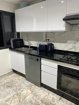 a kitchen with white cabinets and a black counter top at Appartement neuf luxe OLM à Rabat in Rabat
