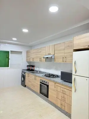 a kitchen with wooden cabinets and a white refrigerator at Nice appartement In Rabat-Temara in Temara