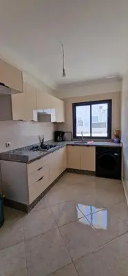 a kitchen with white cabinets and a tile floor at Bel Appartement neuf à 7 min de la plage avec piscine privée in Mohammedia