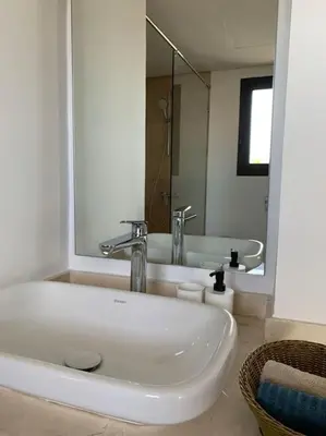 a white bathroom with a sink and a mirror at The Atlantica Ocean view apartment in Dar Bouazza