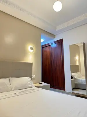 a bedroom with a bed and a wooden door at SUITOUISS - Agdal 3 - Appartement à 2 minutes de la gare de train TGV Rabat in Rabat