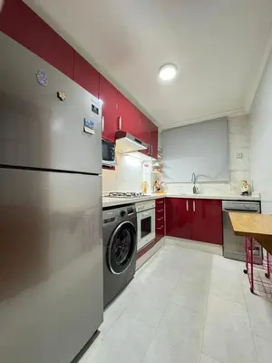a kitchen with a stainless steel refrigerator and red cabinets at SUITOUISS - Agdal 3 - Appartement à 2 minutes de la gare de train TGV Rabat in Rabat