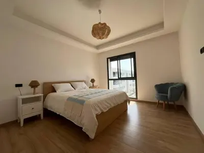 a bedroom with a bed and a chair and a window at Appartement Les pieds dans l'eau in Oulad Kerroum