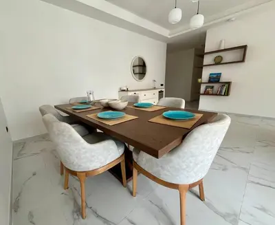 a dining room with a wooden table and chairs at Appartement Les pieds dans l'eau in Oulad Kerroum