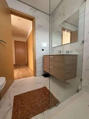 a bathroom with a shower and a sink and a mirror at Appartement Les pieds dans l'eau in Oulad Kerroum