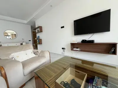 a living room with a couch and a tv on a wall at Appartement Les pieds dans l'eau in Oulad Kerroum