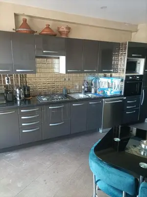 a kitchen with gray cabinets and a blue chair at Casablanca Bourgogne in Casablanca