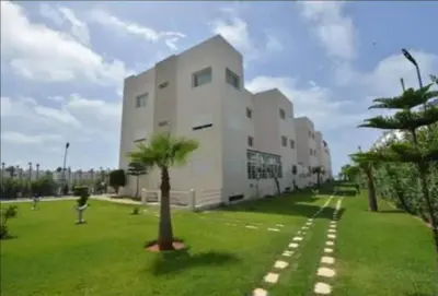 a white building with a palm tree in front of it at Salam Beach, El Mansouria in Pont Blondin