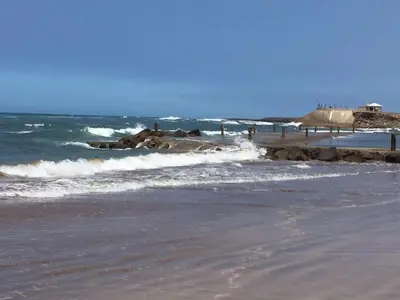 a beach with waves and rocks in the ocean at Salam Beach, El Mansouria in Pont Blondin