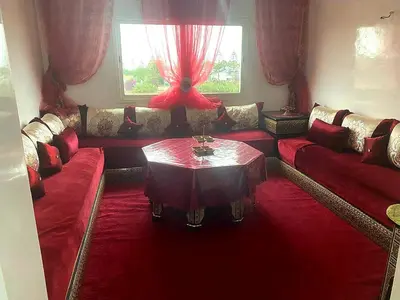 a living room with red couches and a table at Salam Beach, El Mansouria in Pont Blondin