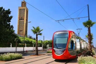 a red tram on a street with palm trees at Cosy sunny 2BR - central near train and tram in Casablanca