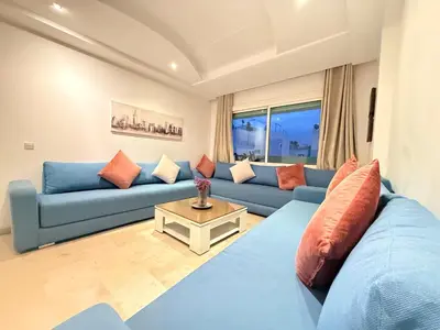 a living room with a blue couch and a table at Cosy sunny 2BR - central near train and tram in Casablanca