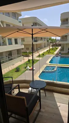 a patio with a table and an umbrella and a pool at appartement haut standing avec piscine a cote de la plage et du golf a bouznika in Bouznika