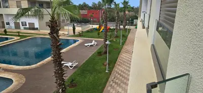 a view of a swimming pool with a palm tree at appartement haut standing avec piscine a cote de la plage et du golf a bouznika in Bouznika