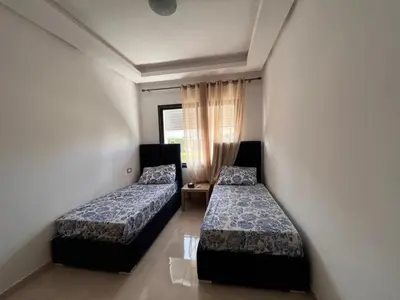 a room with two beds and a window at Salah in Bouznika