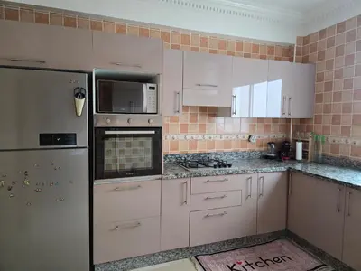 a kitchen with white cabinets and a refrigerator at Superbe appartement meublé, lumineux et idéalement situé in Casablanca