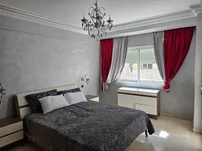 a bedroom with a bed and a chandelier and a window at Superbe appartement meublé, lumineux et idéalement situé in Casablanca