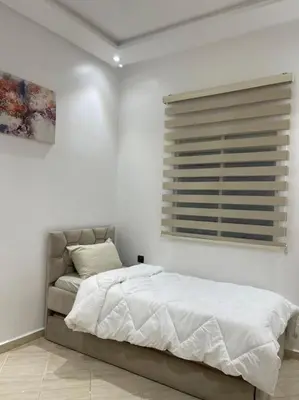 a white bedroom with a bed and a window at Naj'Appartement de charme in Temara