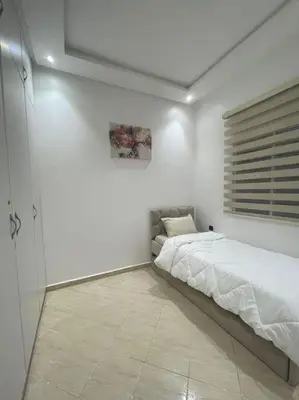 a bedroom with a bed in a white room at Naj'Appartement de charme in Temara