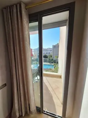 a sliding glass door with a view of a pool at Appartement piscine front de mer in Mohammedia