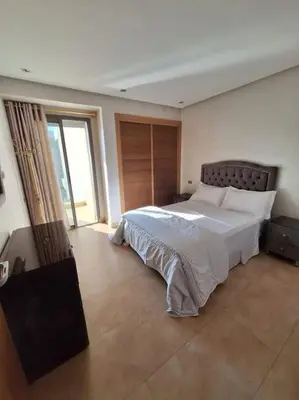 a bedroom with a large bed and a large window at Appartement piscine front de mer in Mohammedia