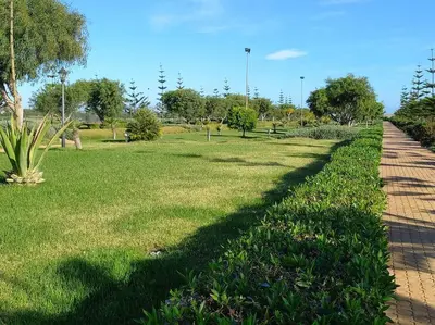 a walkway in a park with grass and trees at Appart à Ola Blanca 2 près de Sidi Rahal in Bir Jedíd Saint-Hubert